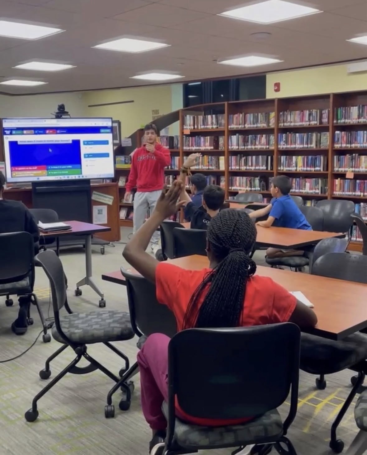 A student raises a hand during the credit score segment in the library.